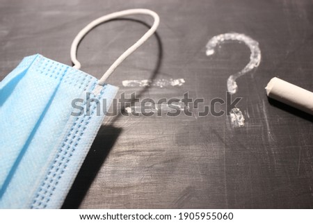 mask objects different and question marks, in chalk on a board as a concept, concept of frequently asked questions to look for the answer to a problem in business, medicine, a close up