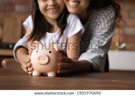 Close up happy young mother and adorable little daughter holding touching pink piggy bank, caring mum and adorable girl child saving money for future, family insurance and investment concept Royalty-Free Stock Photo #1905970690