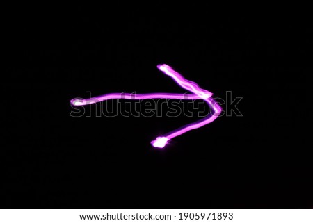 Arrow sign drawn with purple light. Long exposure.