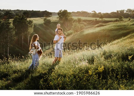 Young beautiful family with a little daughter hug, kiss and walk in nature. Photo of a family with a small child in nature. Royalty-Free Stock Photo #1905986626