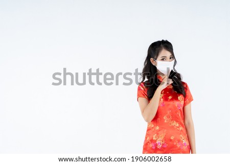 beauty woman wear cheongsam and be quiet with finger on lips with medical mask in chinese new year on white background