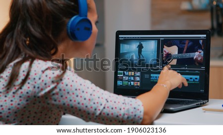 Videographer working on laptop from home, editing video and audio footage at night. Woman content creator using professional device modern technology network wireless processing film montage.