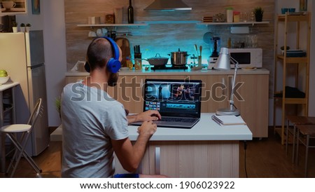 Creative filmmaker editing video footage in home using modern technology. Man content creator in home working on montage of film in new software for editing late at night.