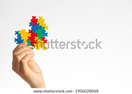 World autism awareness day concept. Child hands holding colorful puzzle heart on white background