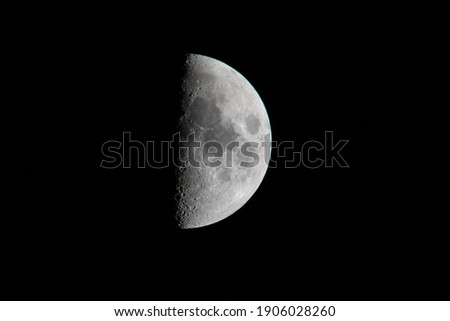 Half moon with detailed craters on the surface in black background
