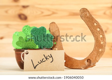 St.Patrick's Day. Clover leafs with golden horseshoe and word Lucky on brown wooden background