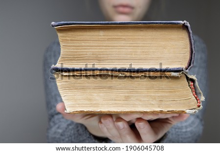 young girl holds out two old books in the palm of our hand. High quality photo