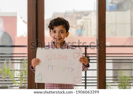 Little boy holding mothers day poster