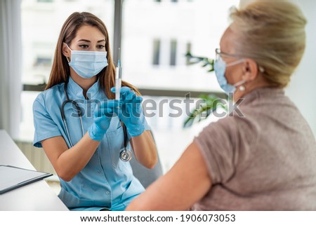 Female doctor giving a consultation to a senior patient.Doctor vaccinating senior patient in clinic.People,medicine and healthcare concept. Royalty-Free Stock Photo #1906073053
