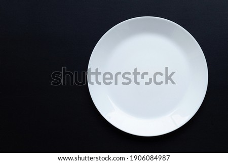 Empty white dish plate on dark background. Top view