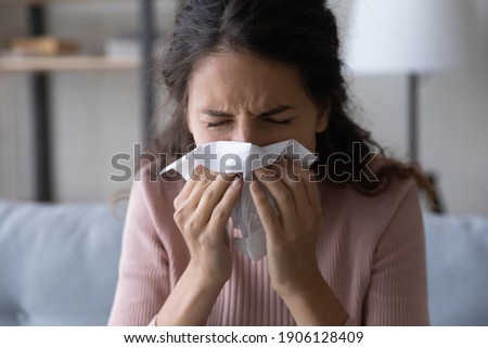 Head shot unhealthy millennial caucasian woman using paper tissue, blowing nose, suffering from first grippe infection symptoms or having seasonal allergic reaction, needs illness medication. Royalty-Free Stock Photo #1906128409