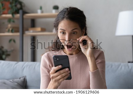 Head shot emotional young woman looking at smartphone screen with opened mouth, feeling surprised with received offer. Amazed millennial lady getting sms with unbelievable news. shocked by sale prices Royalty-Free Stock Photo #1906129606