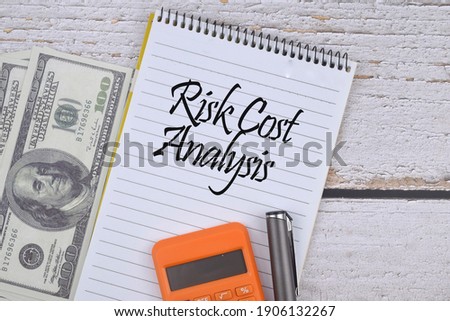 Selective focus image of bank note, calculator and pen with Risk Cost Analysis wording on a wooden background