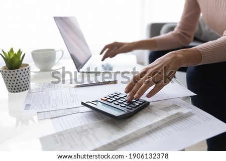 Close up young woman calculating monthly domestic utility bills using computer e-banking application, making rental or medical insurance payment online, managing expenses, doing financial paperwork. Royalty-Free Stock Photo #1906132378