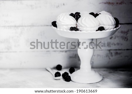 Meringue cookies with blackberries on rustic background