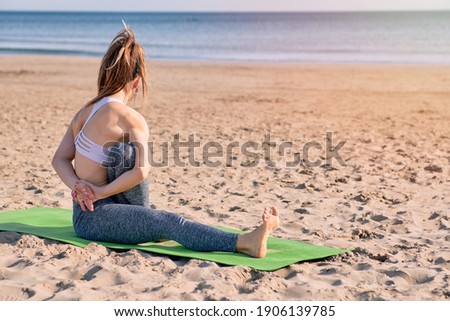 young girl practicing yoga on the beach