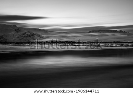 Black and White Photo of a Frozen Lake and Snowy Mountains in the Background. Majestic Glacier View. Beauty of Iceland Nature.