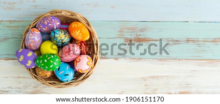 Banner picture of colorful painted egg in basket on blue wooden table prepare for celebrate easter day