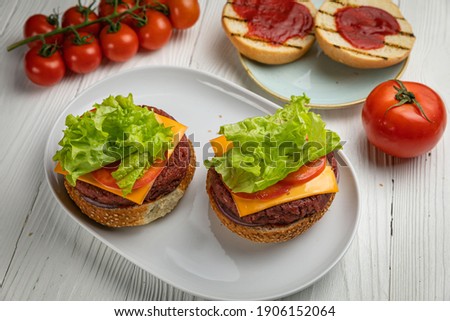 Sandwiches with cutlet, salad, tomato. On a white wooden table
