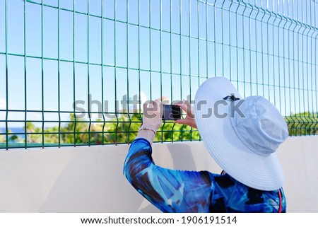 Senior woman take photos using smartphone on a rooftop. Travel and senior lifestyle technology background.