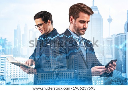 Two entrepreneurs in suits working on new venture capital and hi-tech start up and try to forecast risks and estimate prospective earning growth. Hologram chart on Kuala Lumpur background.