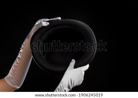 Hand gestures. The magician shows tricks with a hat. Black background