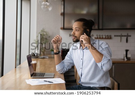 Young african male qualified specialist talk to client hold phone at ear consult explain project detail. Black man marketing expert speak by cell direct boss leader attention to changes in total sales
