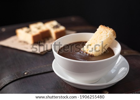 Hot chocolate in white mug with sponge cake on a brown old suitcase
