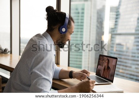 Attentive black guy student take individual video lesson of english communicate with pleasant female tutor on pc screen. African man in headset improve skills in foreign language prepare for exam test Royalty-Free Stock Photo #1906256344
