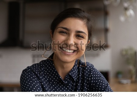 Pleasant smiling young indian woman freelancer looking at camera consult client from computer phone screen via video call. Headshot portrait of mixed race lady taking part in web conference from home Royalty-Free Stock Photo #1906256635