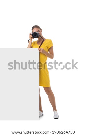 Full length portrait of young beautiful photographer girl with the camera and blank banner isolated on white background