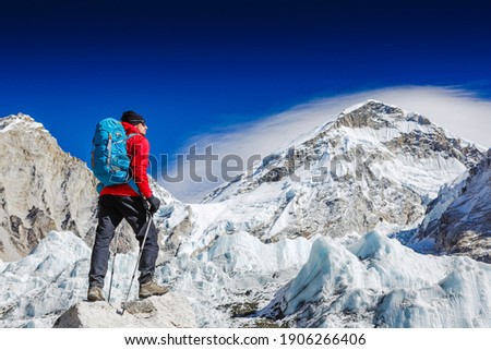 Male backpacker enjoying the view on mountain walk in Himalayas. Face to face with mount Everest, Earth's highest mountain. Travel, adventure, sport concept Royalty-Free Stock Photo #1906266406