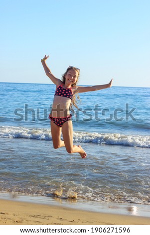 Cute Teenager Girl playing In Sea Waves. Jump Accompanied By Water Splashes. Summer  Day, Happy childhood, Ocean Coast concept