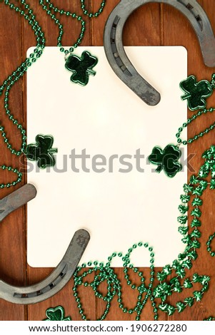 Concept of St. Patrick. Green clover necklaces and lucky horseshoes with poker cards on wooden background, top view place for text