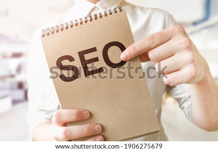 Text SEO on brown paper notepad in businessman hands in office. Business concept
