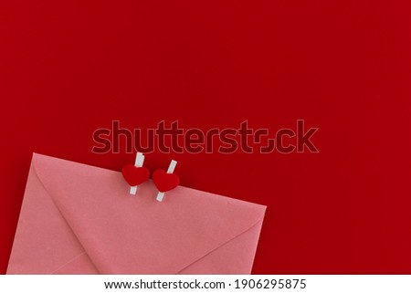 Top view photo of pink envelope with two pins in shape of heart isolated on red background. Holidays mail. The concept of Valentine's Day background. Holiday mockup. Love letter. Romantic love letter