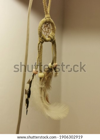 A little dream catcher with a feather hangs from a lamp.