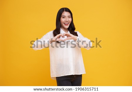 Young beautiful Asian woman showing heart sign isolated on yellow background. love and happy valentine concept. Royalty-Free Stock Photo #1906315711