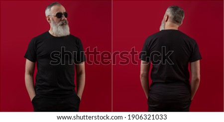 Adult handsome senior male model with a gray beard wearing a white t-shirt. Back view. Mock up space for your logo or design over dark red background
