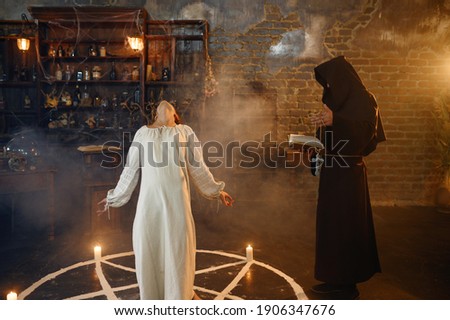 Exorcist in hood casting out demons from a woman Royalty-Free Stock Photo #1906347676