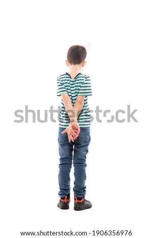 Back view of sad unhappy young boy with Easter bunny ears looking down with hands behind back. Full length isolated on white background. Royalty-Free Stock Photo #1906356976
