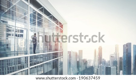 Businessman standing on a balcony and looking at city 