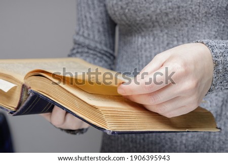 the hand of an invisible person leafs through the pages of an old and old book. in a university or school library. High quality photo