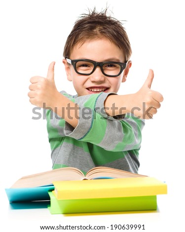 Cute little girl is reading a book and showing thumb up sign using both hands, isolated over white