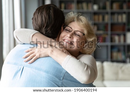Head shot sincere loving middle aged older woman in eyeglasses cuddling affectionate grown son, meeting on weekend at parent's house, showing care and devotion, different generations family relations. Royalty-Free Stock Photo #1906400194