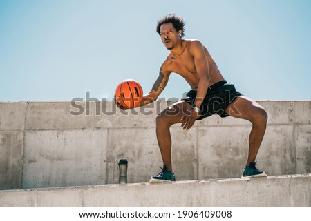 Afro athlete man playing basketball outdoors.