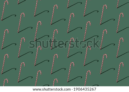Candy cane on green pastel background. Minimal Christmas concept. New Year festive pattern. Flatlay. Holiday layout.