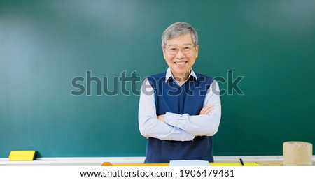 asian senior male professor arm crossed and smile at you in front of blackboard in the college classroom Royalty-Free Stock Photo #1906479481