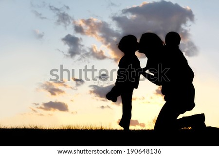 the Silhouette of a mother and her two young children; a little boy and his baby brother are playing outside at sunset, hugging and kissing on a summer day. Royalty-Free Stock Photo #190648136