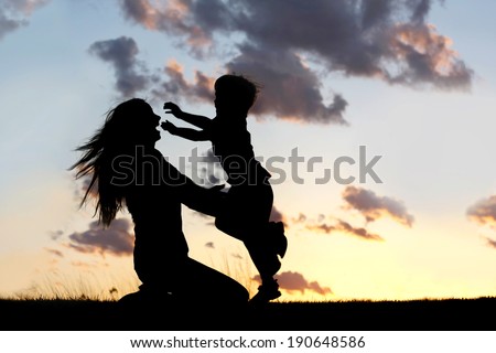 a silhouette of a happy young boy child running into the arms of his loving mother for a hug, in front of the sunset in the sky on a summer day. Royalty-Free Stock Photo #190648586